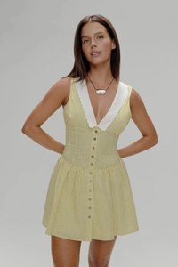 Détail du col en V blanc et de la fermeture à boutons sur la robe jaune à pois