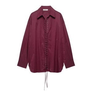 Detail of burgundy V-neck blouse featuring unique lace-up front and buttoned long sleeves