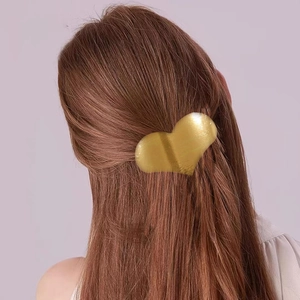 Elegant gold heart-shaped metal hair clip with brushed finish on model's brown hair