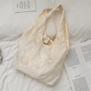 Close-up of French vintage beige lace tote bag with floral embroidery on white fabric