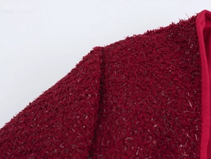 Détail de la texture en tweed rouge foncé sur l'épaule et le col de ce vêtement