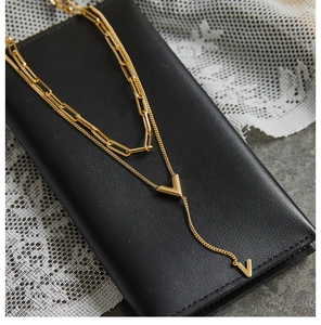 Detail of double-layered 18K gold-plated V-pendant necklace on premium leather wallet