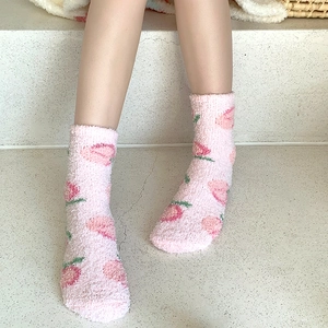 Gros plan de chaussettes en polaire corail rose avec motifs fraises portées par un mannequin