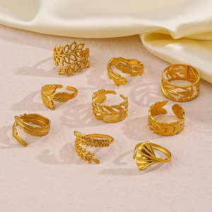 Macro detail of nine 18K gold-plated stainless steel leaf rings set on silk fabric