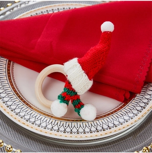 Dettaglio di un portatovagliolo natalizio in maglia con cappellino su un piatto decorato