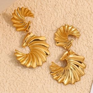 Boucles d'oreilles ailes en plaqué or 18K avec texture spirale sur fond beige en relief