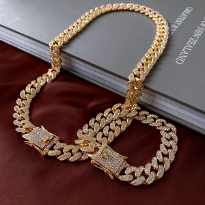 Macro detail of gold Cuban link chain with white zircons on dark red silk background