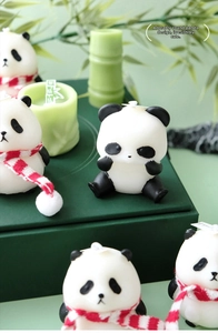 Detailed view of cute panda-shaped scented candles with scarf on green bamboo background