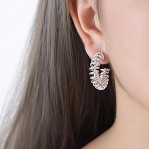 Macro shot of silver-colored multi-layer spiral spring texture hoop earring on ear
