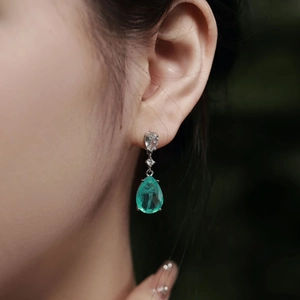 Close-up of elegant 925 silver earrings with pear-cut emerald zircon on model