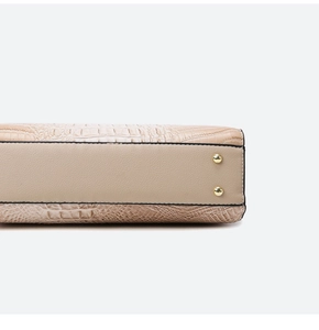Detail view of beige crocodile embossed leather bag base with golden protective metal feet