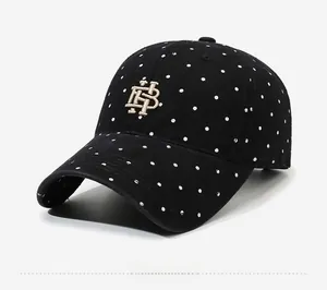Detail view of black washed cotton baseball cap with white polka dots and gold embroidery