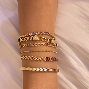 Vue détaillée de bracelets dorés superposés avec zircons colorés et breloque cœur