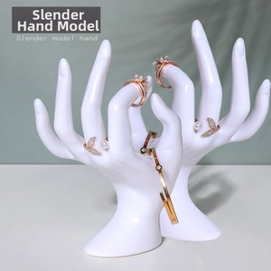 Detailed view of white resin hand model displaying rose gold rings and metal bracelet