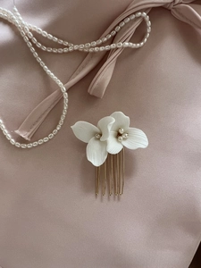 Close-up of white ceramic flowers and freshwater pearls on elegant bridal hair comb