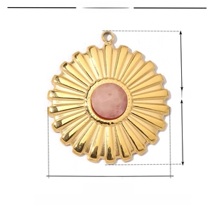 Macro detail of sunburst pendant in gold stainless steel with pink natural stone inlay