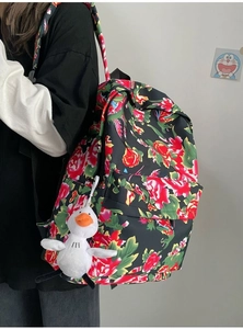 Side view of floral backpack with red roses and a white duck plush charm pendant