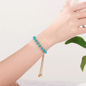 Bracelet ajustable en chaîne dorée avec perles turquoises bleues sur poignet et décor floral