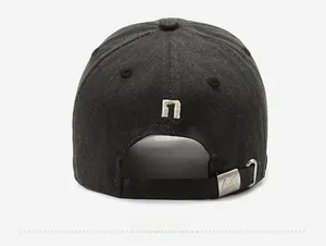 Detail view of cotton baseball cap back featuring small letter embroidery and metal buckle