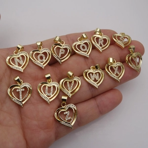 Golden heart-shaped letter pendants with cubic zirconia inlay held in a hand