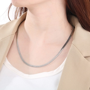 Primo piano di una collana a catena barbazzale argento indossata da un modello trendy