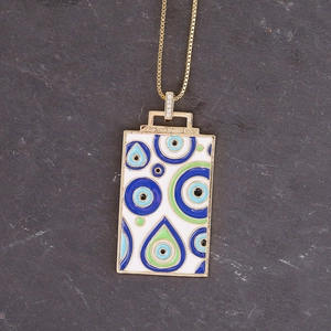 Macro detail of square evil eye pendant with blue enamel and crystal inlay on gold necklace