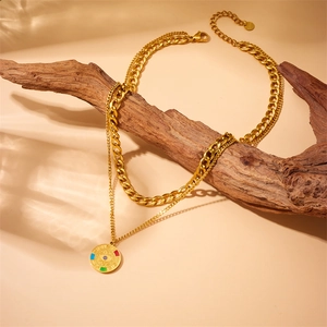Detail of gold double-layer necklace with enamel evil eye pendant on a rustic wood branch