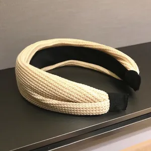 Detail of beige knitted headband featuring tight weave texture and black non-slip lining