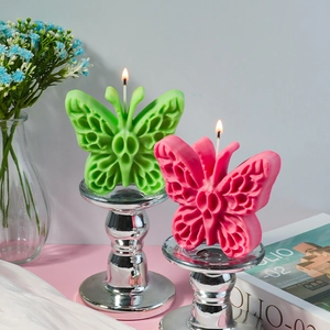 Dettaglio di candele a forma di farfalla in verde e rosa su basi in argento