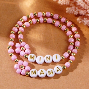 Detailed view of pink beaded MAMA and MINI bracelet set with golden flower accents