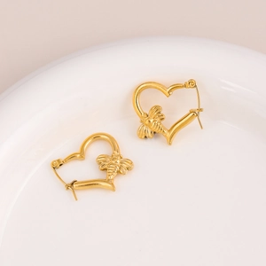Golden stainless steel heart-shaped hoop earrings with bee charm on ceramic plate