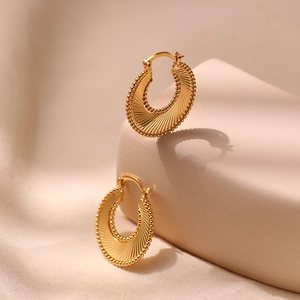 Macro view of textured fan-shaped 18K gold-plated hoop earrings with beaded edges