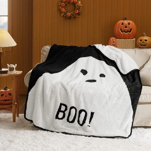 Close-up of Halloween ghost blanket with 'BOO!' text on a sofa with cozy festive decor