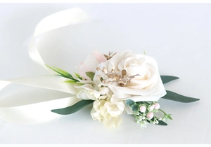 Detail of cream rose wrist corsage with golden leaves and white satin ribbon tie