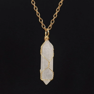 Detailed macro view of handmade wire-wrapped white crystal hexagonal pendant on gold chain