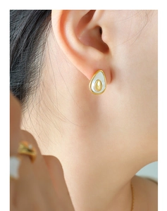 Close-up of elegant avocado-shaped stud earring with gold frame and mother of pearl inlay