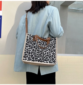 Lifestyle view of women's leopard print canvas tote bag with brown straps and long shoulder belt