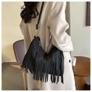 Detail of matte leather fringe bag with gold-tone hardware on casual model look