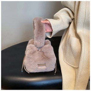 Close-up of light brown faux fur bucket bag with nice every day label and drawstring