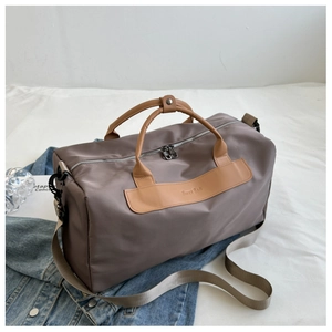 Large taupe nylon sports bag on denim jacket with brown handles and shoulder strap