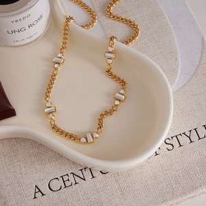 Collier chaîne dorée classique avec cristaux rectangulaires et ronds sur plateau céramique