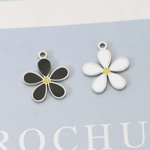 Detail of flower enamel pendants in black and white with 18K gold plated copper base