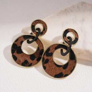 Detail of leopard print double hoop earrings with golden metal edges on a marble base