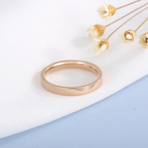 Macro detail of a 3mm polished rose gold stainless steel ring on elegant white fabric