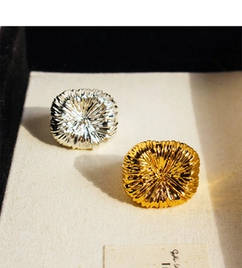 Macro view of gold and silver textured rings with sunburst radial pattern on linen