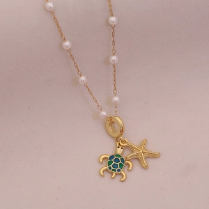 Elegant gold necklace with pearl accents featuring turtle and starfish sea animal pendants