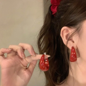 Detail view of retro red resin C-shape hoop earrings worn by a model for a vintage look