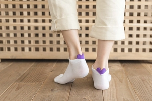Detail of white cotton ankle socks featuring a purple heart embroidery on the heel area