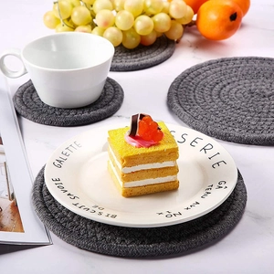 Macro shot of dark grey braided cotton placemat on a marble table with lifestyle props