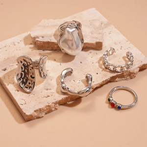 Detail of 5-piece silver ring set with irregular shapes, pearls, and gemstones on stone